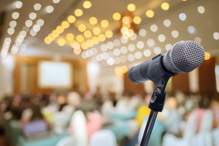 wystąpienia publiczne – zdjęcie mikrofonu na pierwszym planie, w tle sala